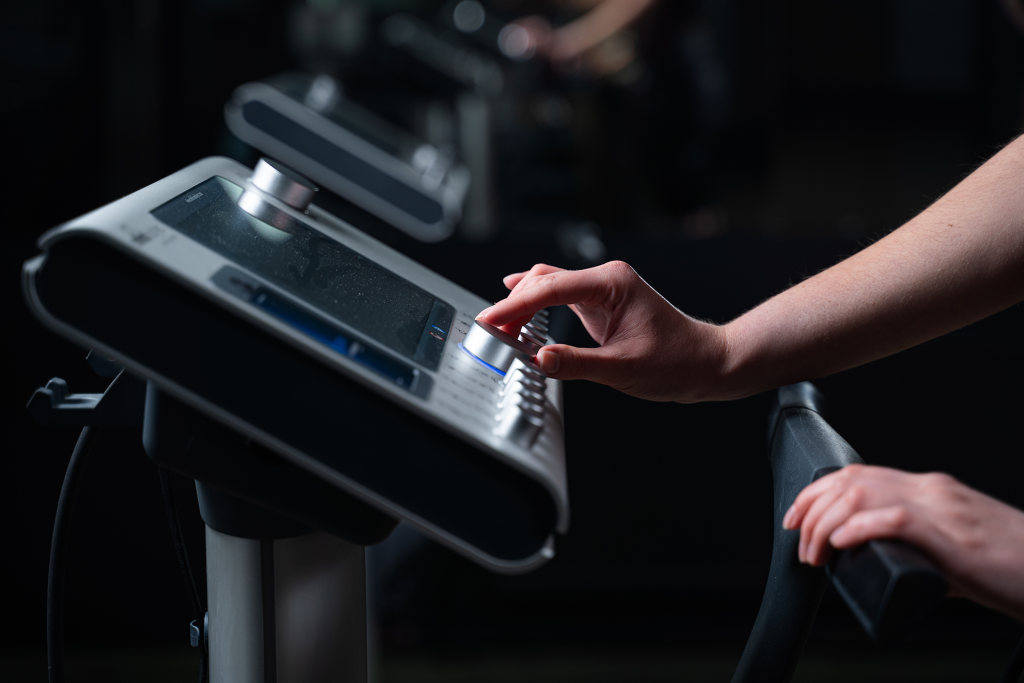 Κοντινό πλάνο σε ρύθμιση έντασης μηχανήματος EMS κατά τη διάρκεια προπόνησης, που αναδεικνύει τη στοχευμένη μυϊκή ενεργοποίηση